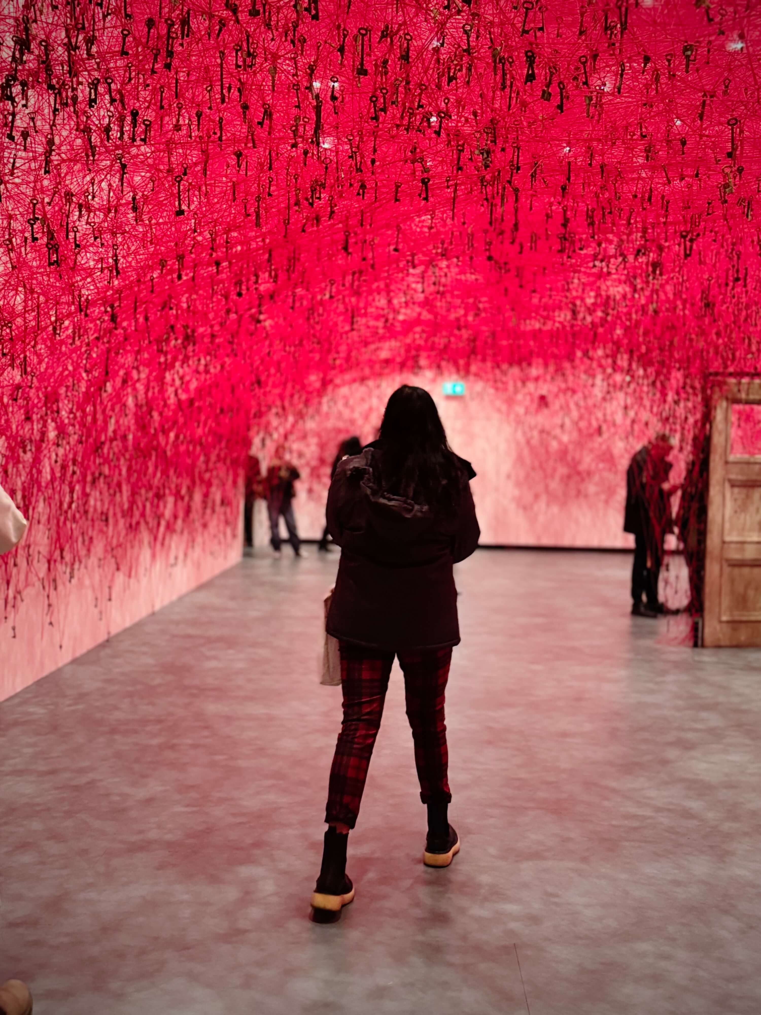 Visitor standing within the red thread installation